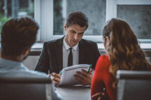 A couple sits with a lawyer at a desk reviewing documents during a divorce mediation consultation in Connecticut.