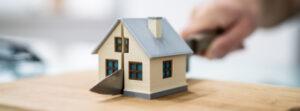 A person holding a knife cuts a house in two to represent the question of who gets the house in a divorce with children in CT.
